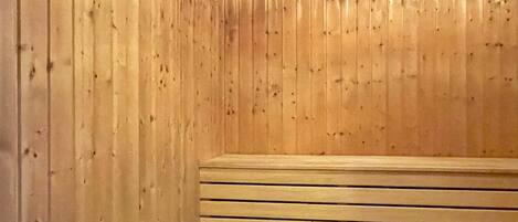 Una sala de sauna con bancos de madera y una tina de hidromasaje.