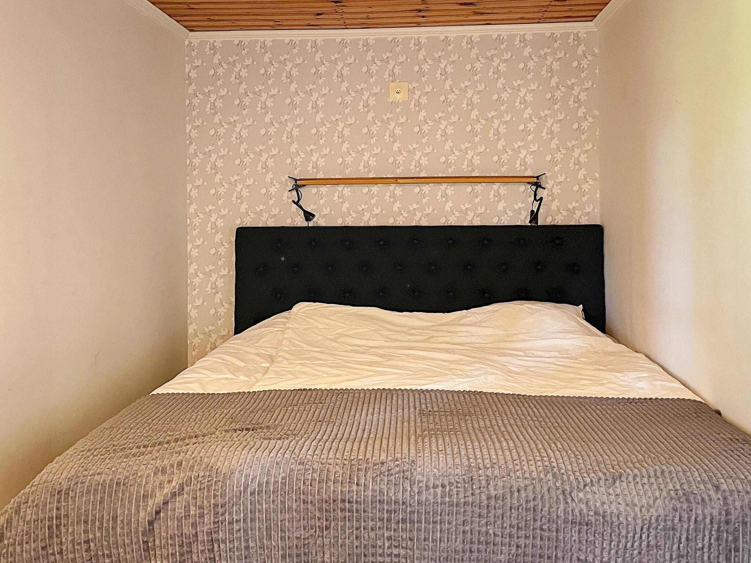 A single bed with a black headboard and a wooden bed frame.