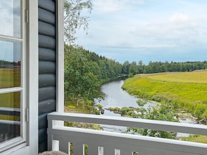A river view from a porch with a railing, a window, and a view of a forested area. - 4 Star Holiday Home in Mellerud (Mellerud)