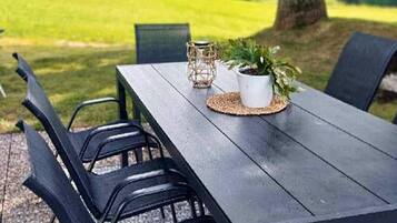 An outdoor dining area with a table, chairs, and a potted plant.