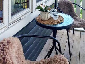 A covered outdoor seating area with a round table and two chairs, a potted plant, and a glass on the table. - 4 Star Holiday Home in Mellerud (Mellerud)