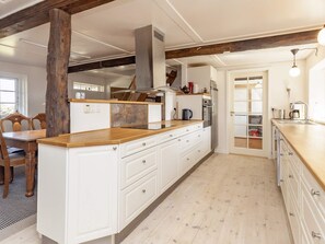 A kitchen with white cabinetry, a wooden countertop, and a built-in stove. - 6 Person Holiday Home in Guldborg (Guldborg)