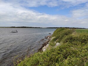 A calm lake with boats, a grassy shoreline, and a distant tree line. - 6 Person Holiday Home in Guldborg (Guldborg)