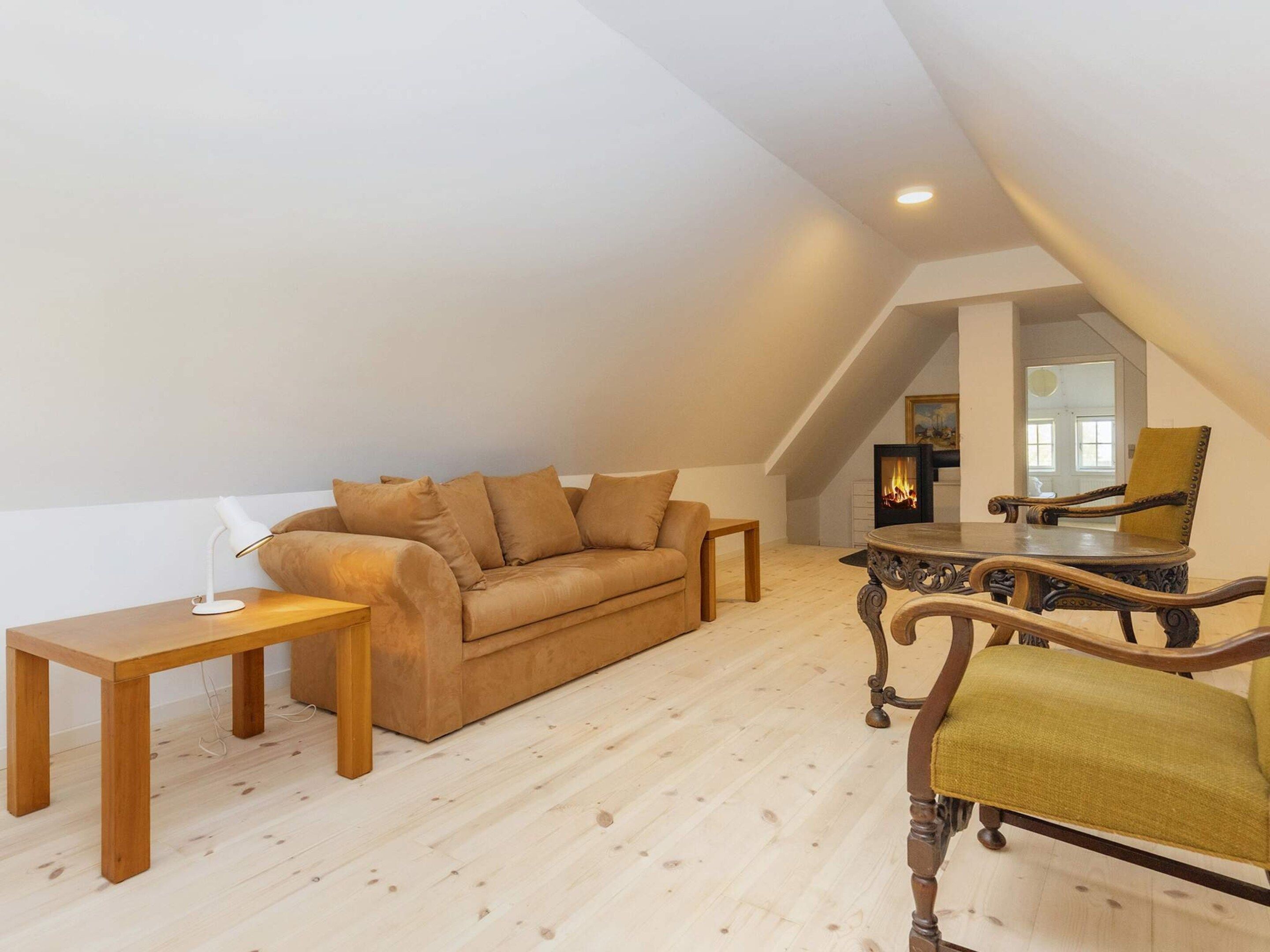 Un salon de style industriel, avec un plancher en bois, un canapé beige, une petite table avec une lampe et une chaise en bois.