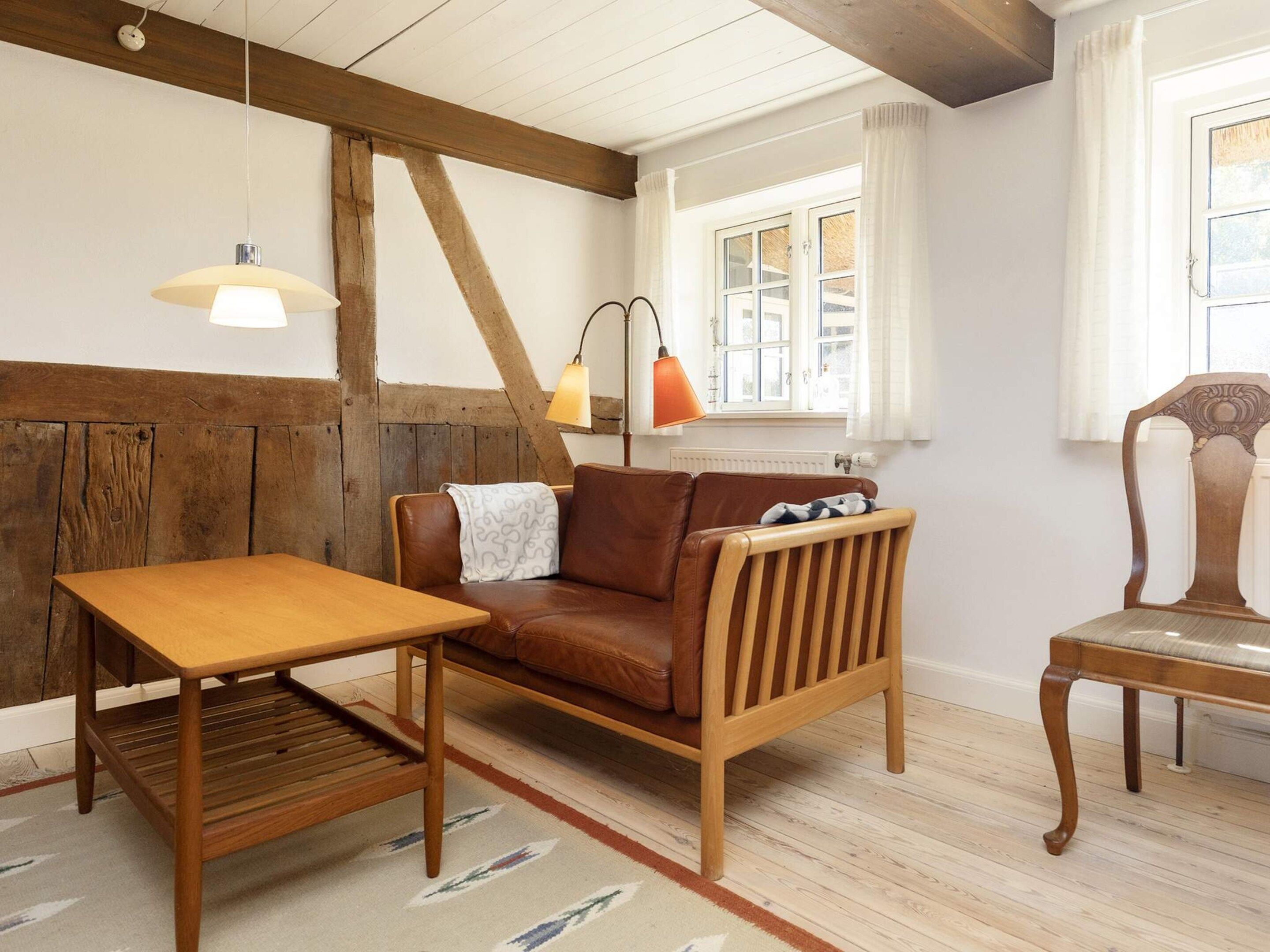 A cozy room with a wooden bench, a sofa, a table, and a chair.