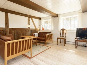 A cozy living room with wooden furniture, a television, and a window with curtains. - 6 Person Holiday Home in Guldborg (Guldborg)