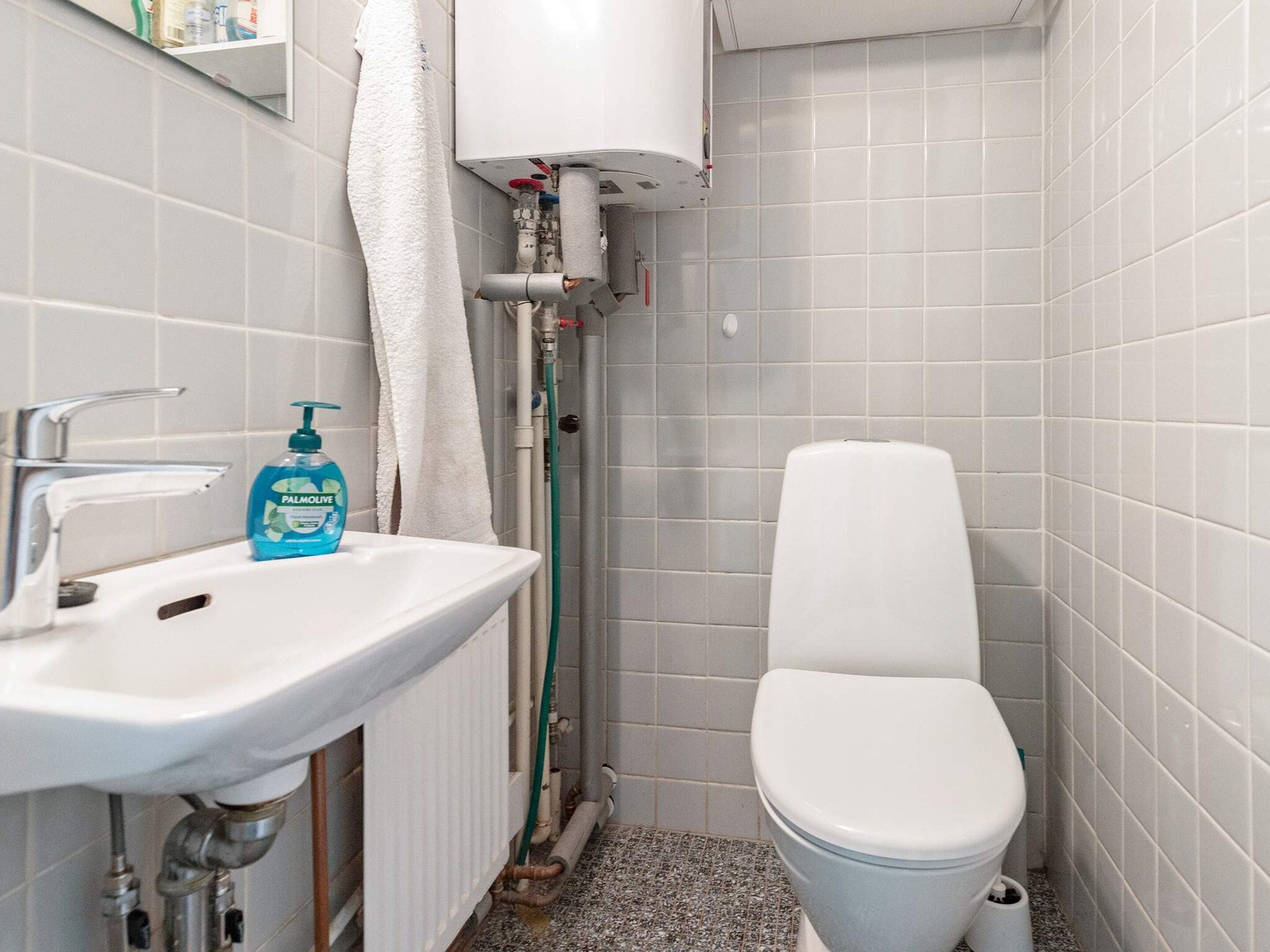 A bathroom with a white sink, a toilet, and a towel hanging on the wall.