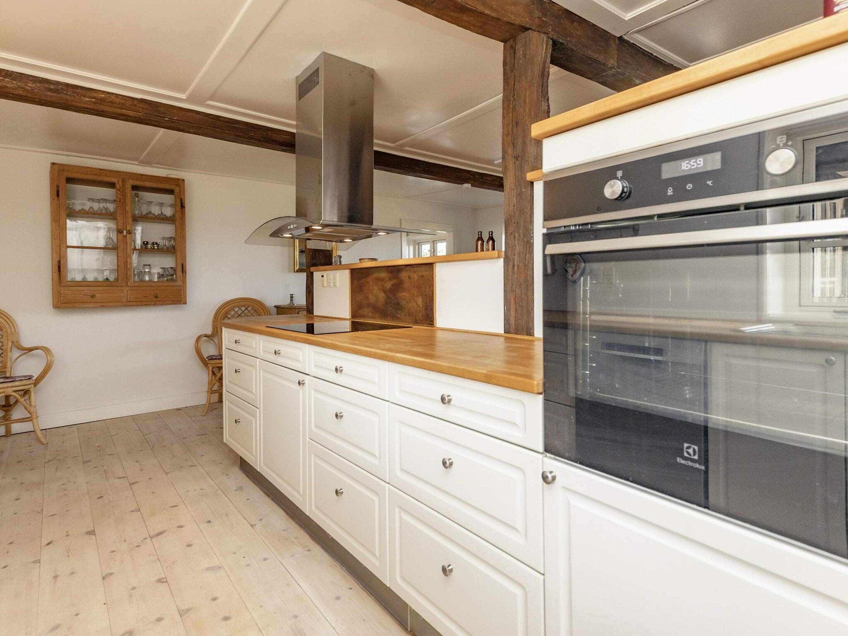 A kitchen with a built-in oven, wooden cabinets, and a window with a view.