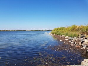 A calm lake with a rocky shoreline and sparse vegetation. - 6 Person Holiday Home in Guldborg (Guldborg)