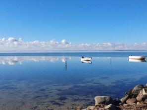 A calm lake with two boats, clear water, and a rocky shoreline. - 6 Person Holiday Home in Guldborg (Guldborg)