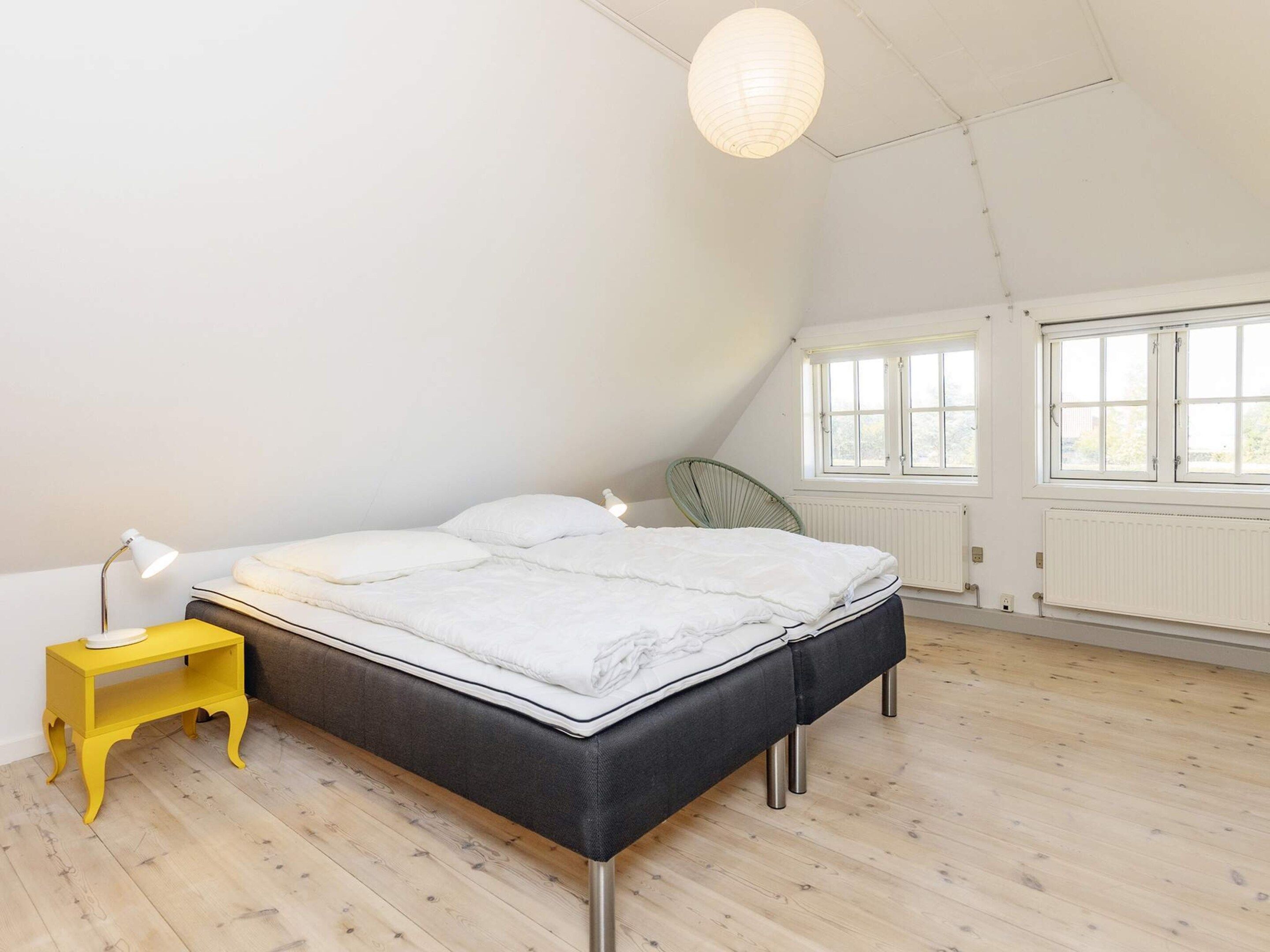 A bedroom with a bed, bedside lamps, a chair, and a window.