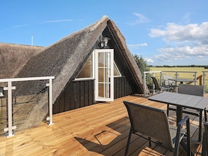 A thatched-roof structure with a wooden deck and outdoor seating. - 6 Person Holiday Home in Guldborg (Guldborg)