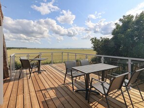 A wooden deck with outdoor furniture, a railing, and a view of a field and trees. - 6 Person Holiday Home in Guldborg (Guldborg)