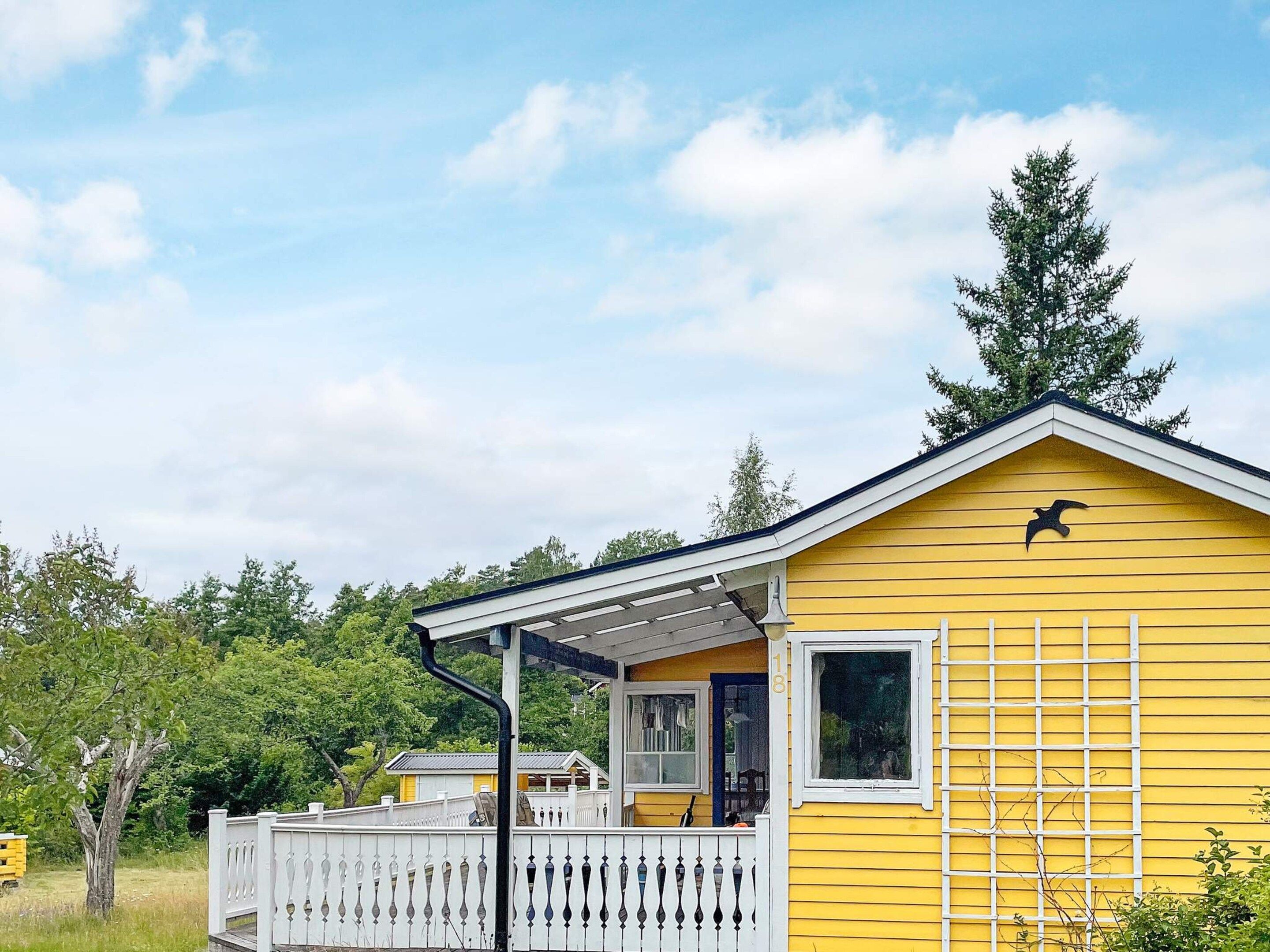 A yellow building with a white porch and a black bird symbol on the roof.