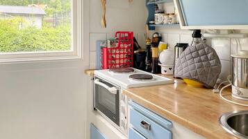 A kitchen with a stove, a sink, and a window overlooking greenery.