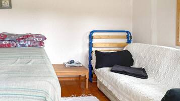 A bedroom with a bed, a sofa, a small table, and a wall-mounted picture frame.