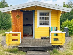 A small yellow cabin with a wooden door, a window, and a small porch area. - 4 Person Holiday Home in Kolmarden (Kolmården)