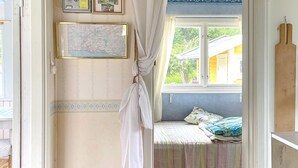 A room with a bed, a window with a view of greenery, a map on the wall, and a wooden shelf. - 4 Person Holiday Home in Kolmarden (Kolmården)