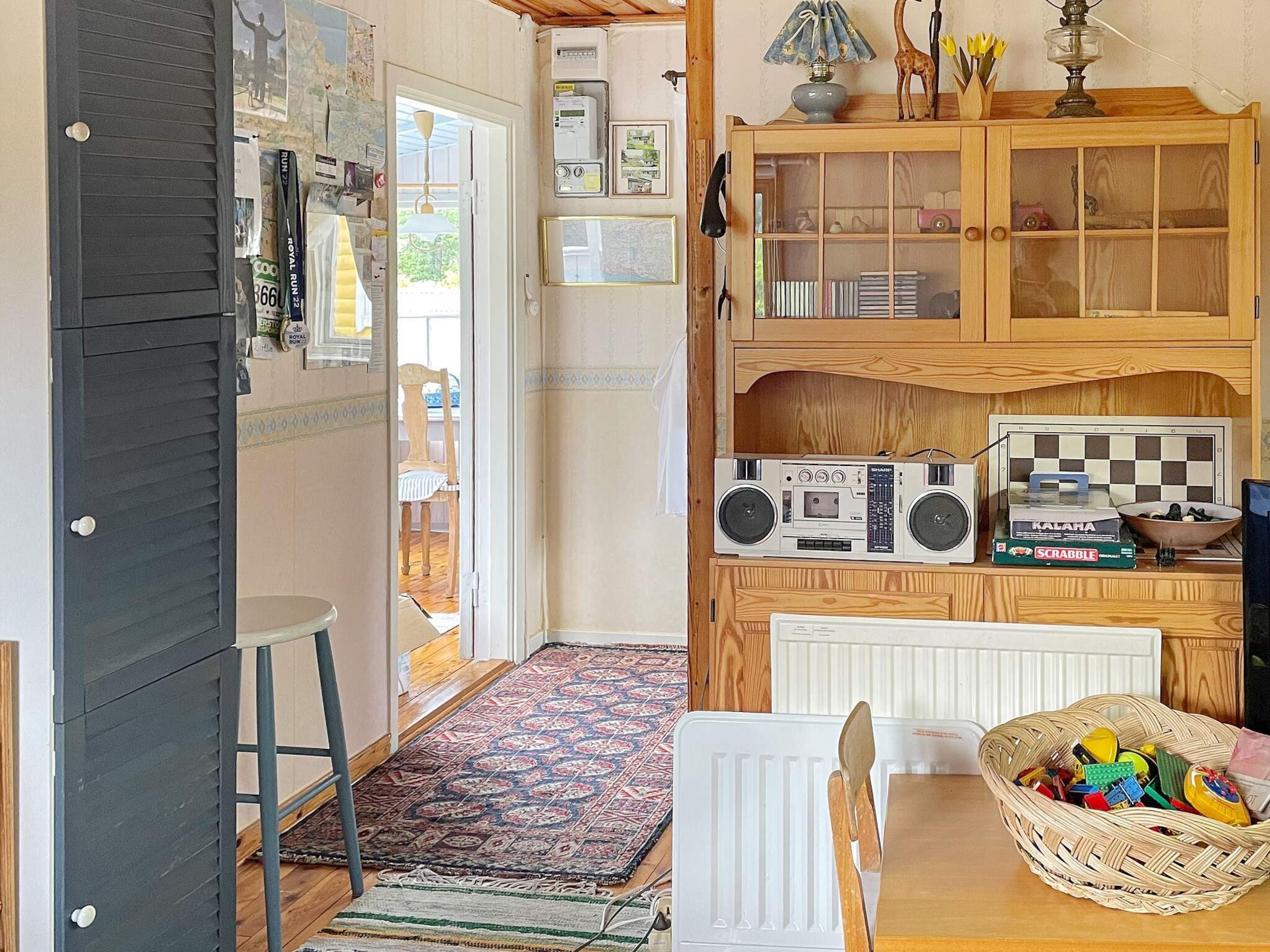 A compact kitchen with a wooden cabinet, a radio, and a Scrabble game.