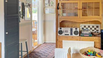 A compact kitchen with a wooden cabinet, a radio, and a Scrabble game.