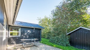 A building with a metal roof, a wooden bench, and a paved area. - 6 Person Holiday Home in Hemmet (Hemmet)
