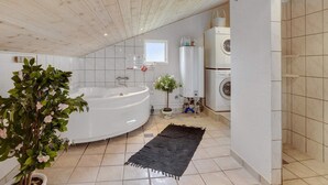 A modern bathroom with a freestanding bathtub, a washing machine, and a small window. - 6 Person Holiday Home in Hemmet (Hemmet)