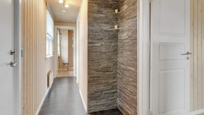 A hallway with wooden paneling, a stone accent wall, and a white door. - 6 Person Holiday Home in Hemmet (Hemmet)