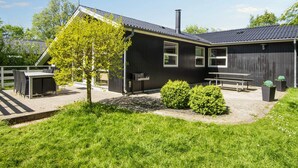 A modern building with a flat roof, a chimney, and a fenced outdoor area with a table and benches. - 6 Person Holiday Home in Hemmet (Hemmet)