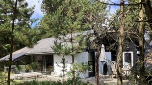 A small, single-story building with a sloped roof, surrounded by dense trees and greenery. - 6 Person Holiday Home in Norre Nebel (Norre Nebel)
