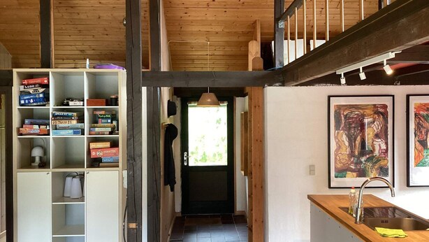 A wooden interior with a staircase, a kitchen area with a sink, and a bookshelf filled with board games. - 6 Person Holiday Home in Norre Nebel (Norre Nebel)