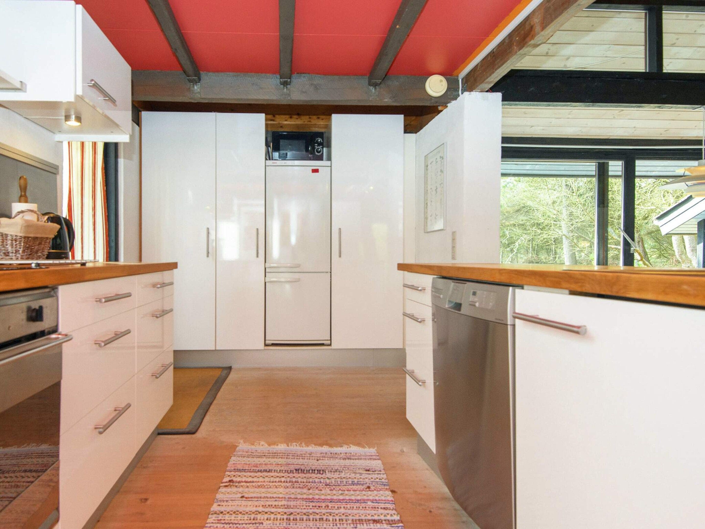 Une cuisine moderne avec des meubles blancs, un four à micro-ondes encastré et un lave-vaisselle.