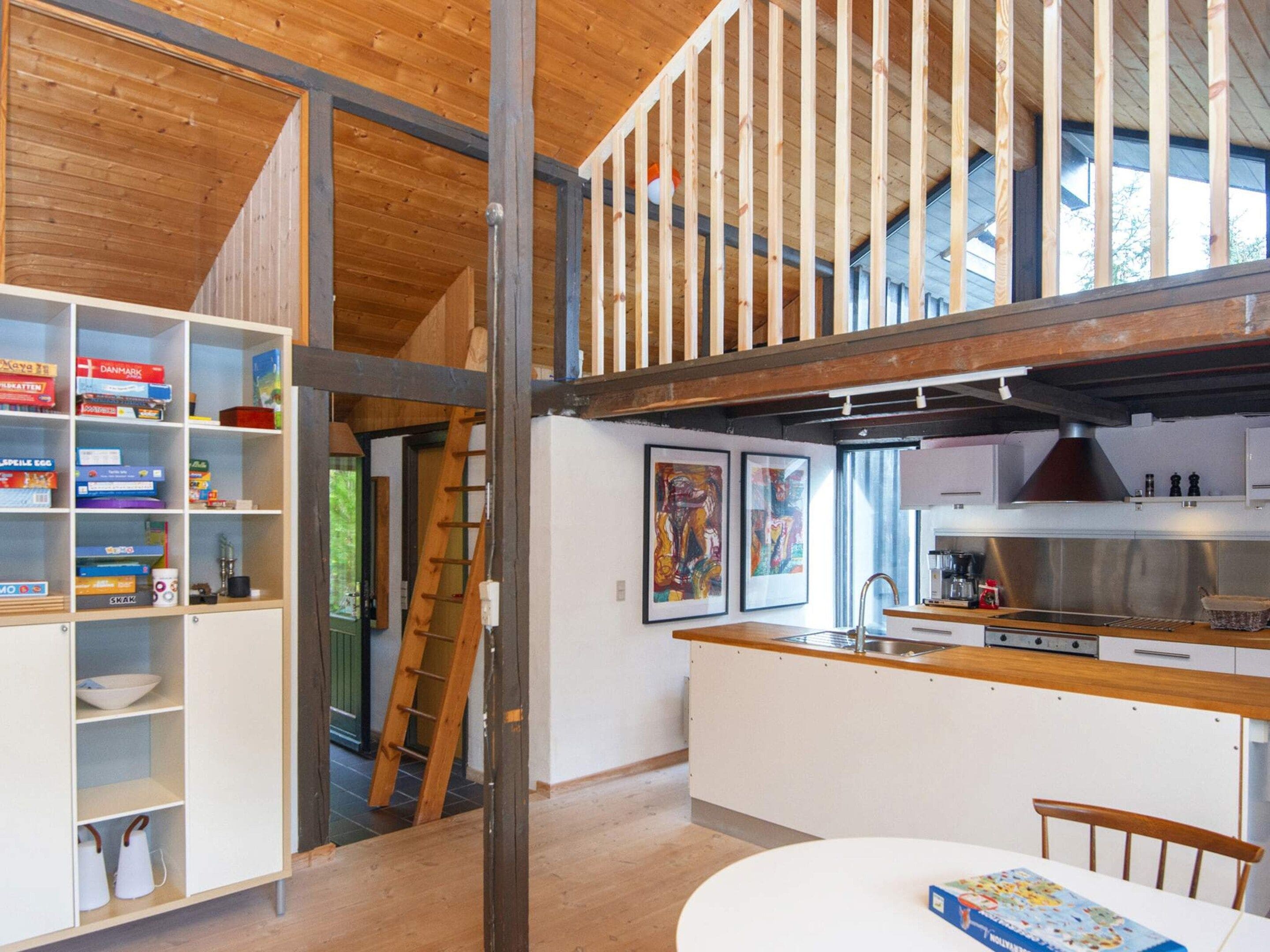 Cozinha moderna com bancada de madeira, uma mesa de jantar e escada para um andar superior.