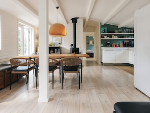 A modern kitchen with a dining area, wooden flooring, and a large window. - 4 Star Holiday Home in Stege (Stege)