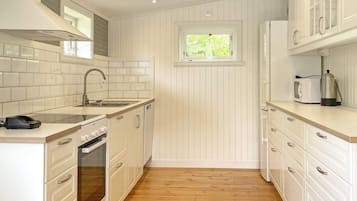 A compact kitchen with white cabinetry, a built-in oven, a sink, and a window above the countertop.