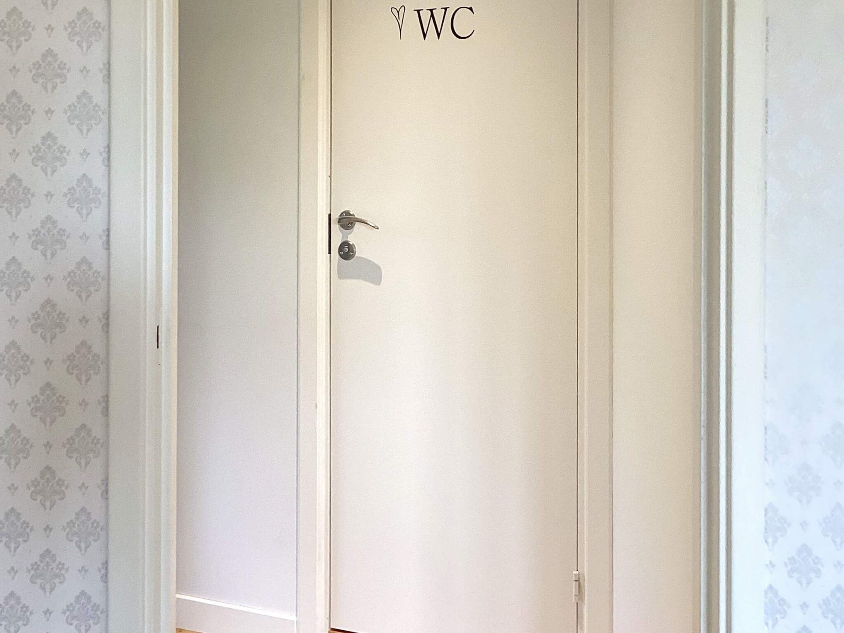A closed door with a lock and a keyhole, marked with 'WC' indicating a restroom.