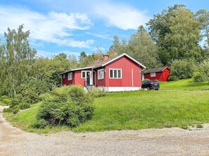 A red house with a porch, surrounded by greenery and a clear sky. - 4 Person Holiday Home in Uddevalla (Uddevalla)