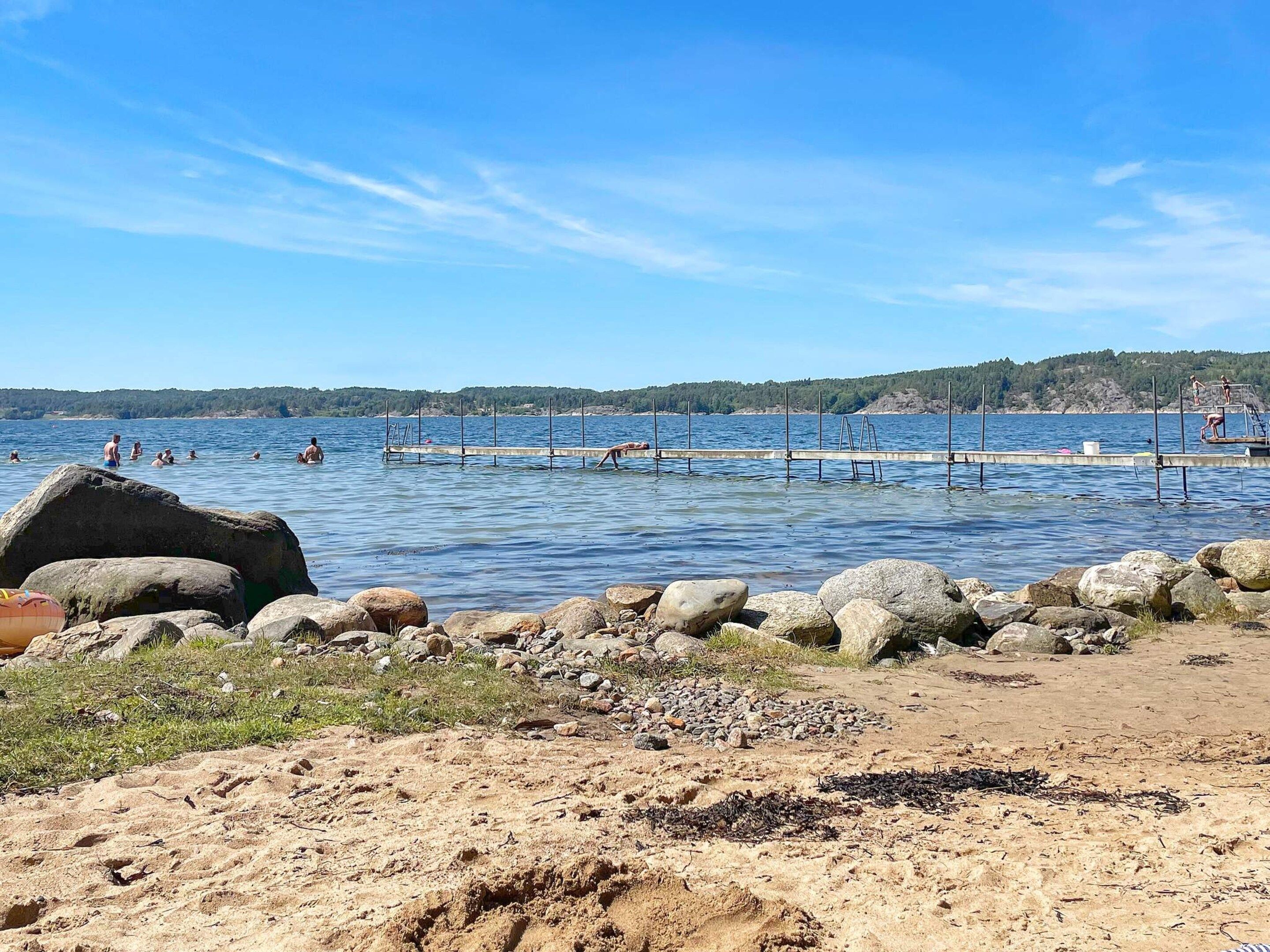 A beach with a pier extending into the water, surrounded by rocks and sand.