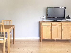 A wooden dining table with chairs, a wooden cabinet with drawers, and a flat-screen TV on top. - 4 Person Holiday Home in Uddevalla (Uddevalla)