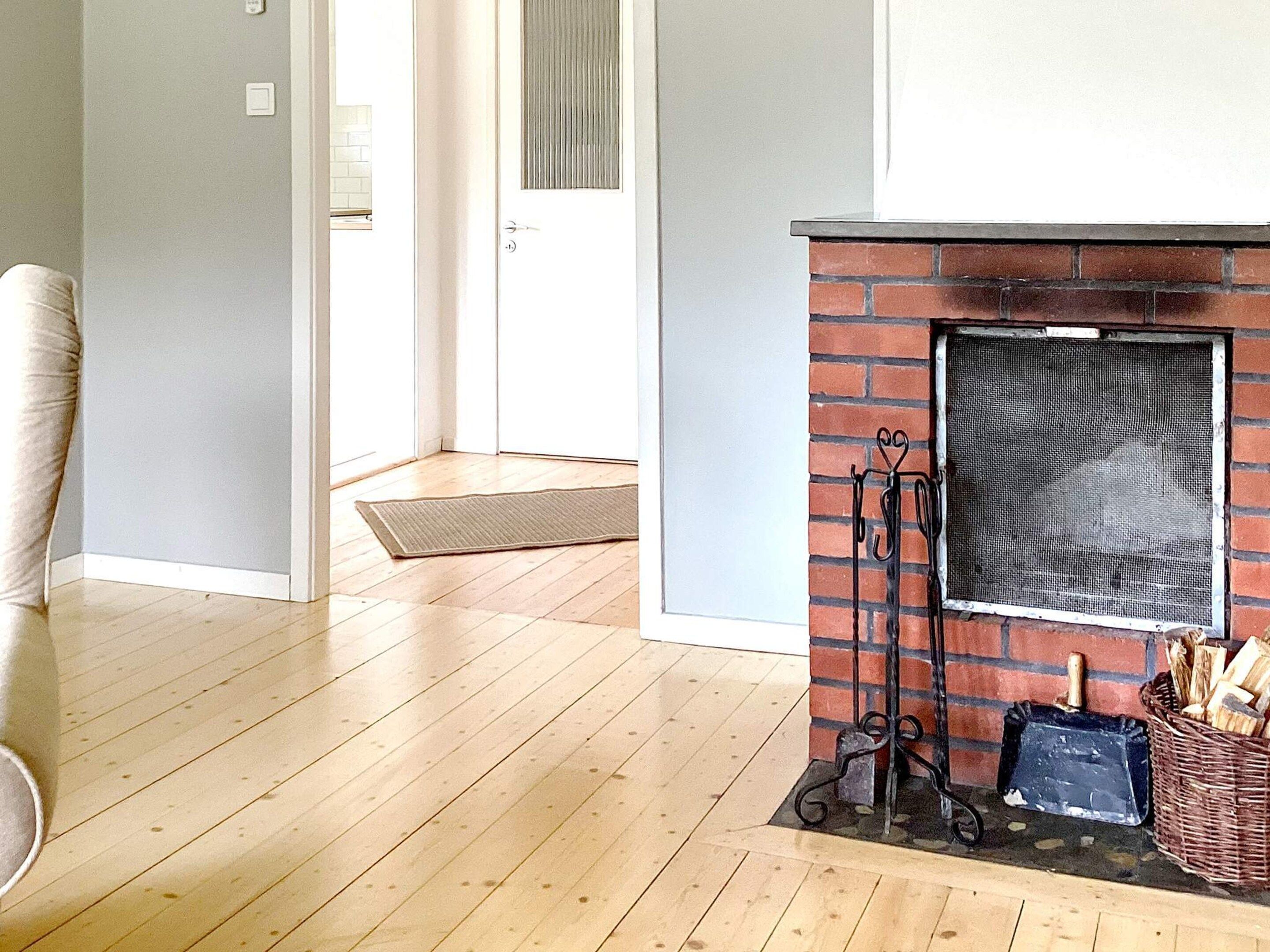 A room with a fireplace, a door, and a wooden floor.