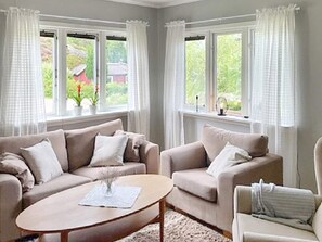 Un salon avec deux canapés, une table basse et une vue sur la verdure à l’extérieur.