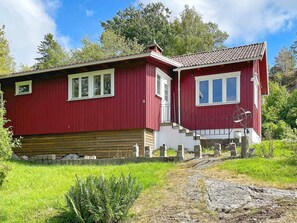 A red wooden house with a stone foundation, white trim, and a small porch. - 4 Person Holiday Home in Uddevalla (Uddevalla)