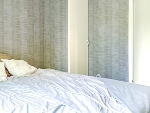 A bedroom with a bed, a wardrobe, and a door. - 4 Person Holiday Home in Uddevalla (Uddevalla)