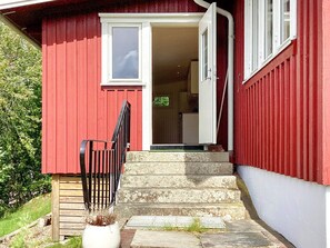 A red building with a wooden door and steps leading to a porch. - 4 Person Holiday Home in Uddevalla (Uddevalla)