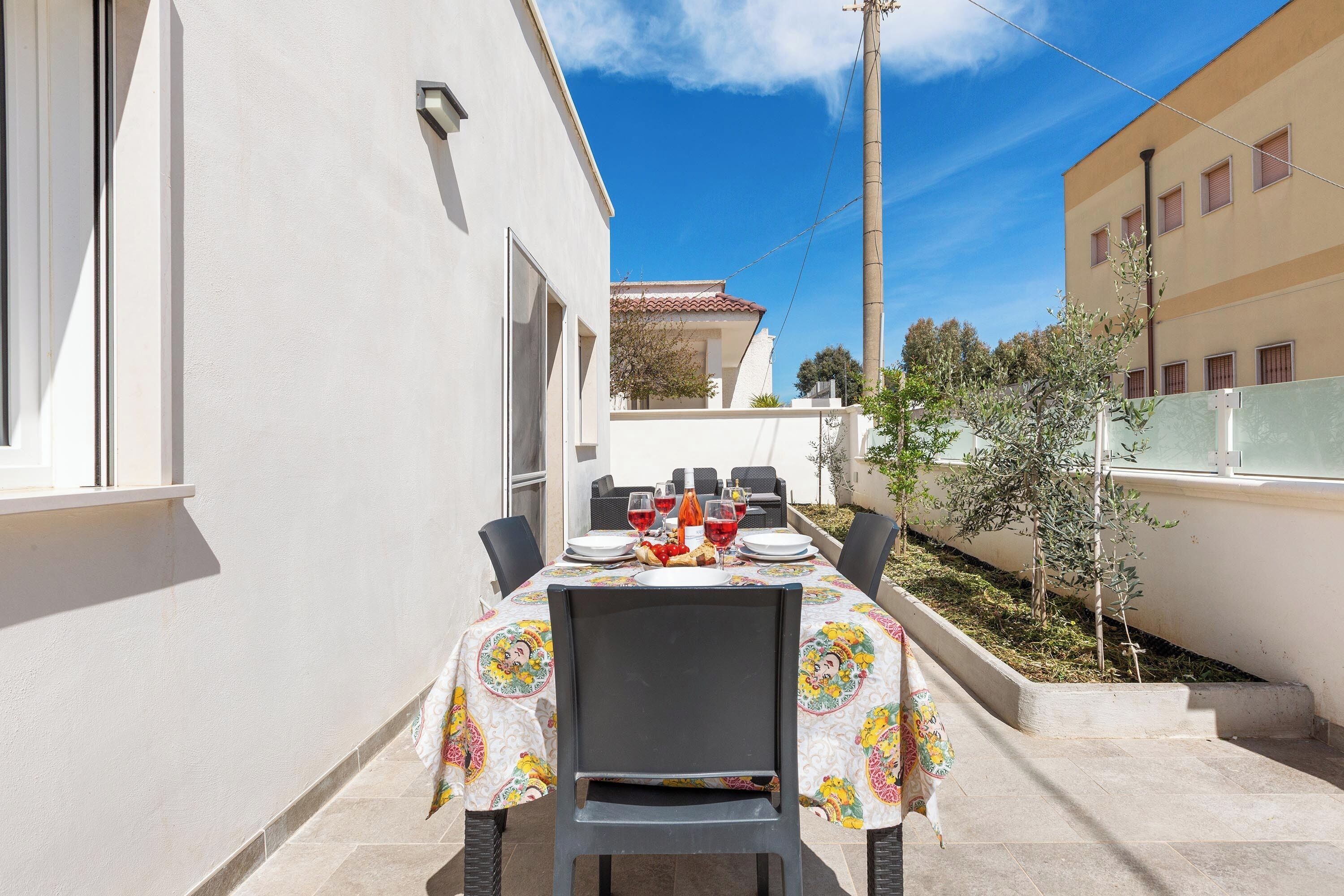 An outdoor dining area with a table set for two, chairs, and a view of a building in the background.