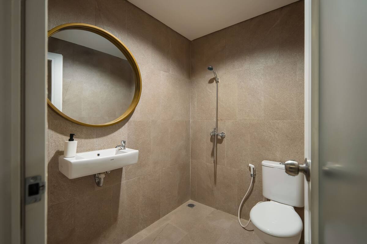 Un baño con lavamanos, espejo, inodoro y ducha.