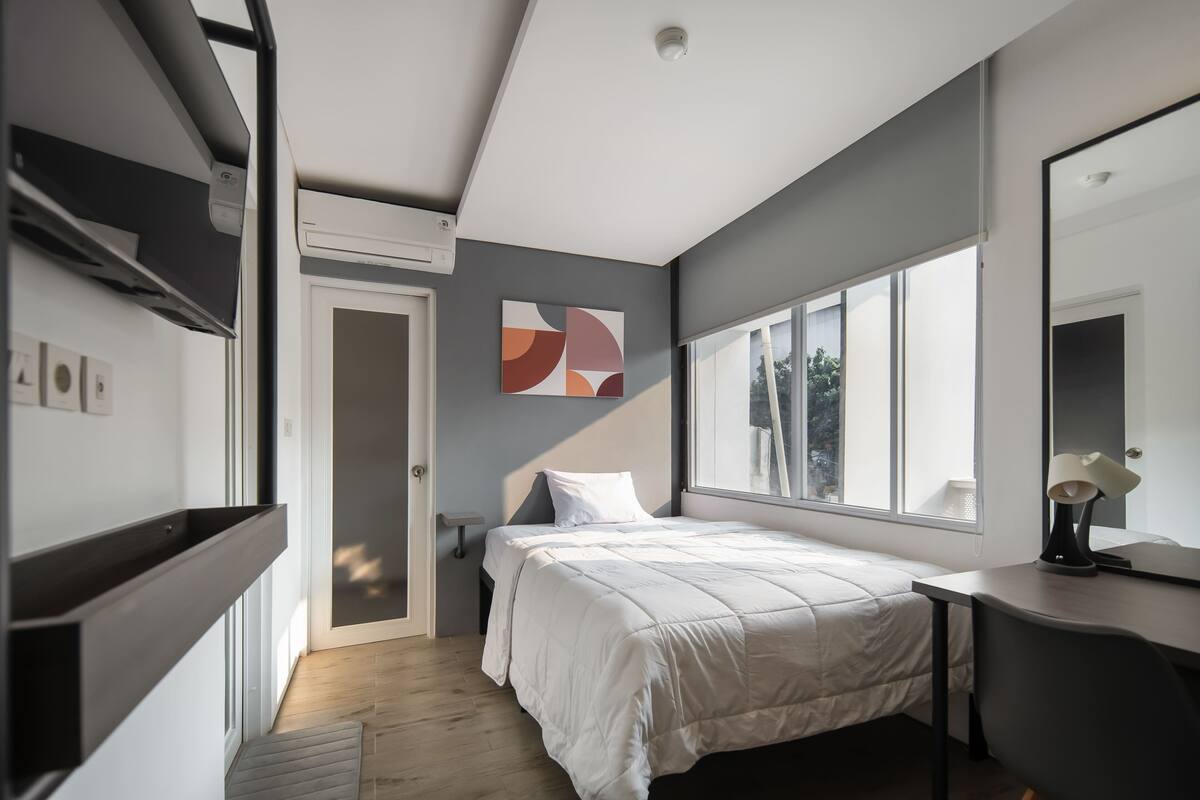 Un dormitorio moderno con cama, mesita de noche y un ventanal grande.