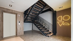 A modern interior with a spiral staircase, a white door, and a wall with geometric light fixtures. - Cove Art Living (Jakarta)