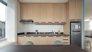 A modern kitchen with wooden cabinets, a stainless steel refrigerator, and a black countertop. - Cove Art Living (Jakarta)