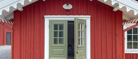 A red wooden building with a white trim and a green door.