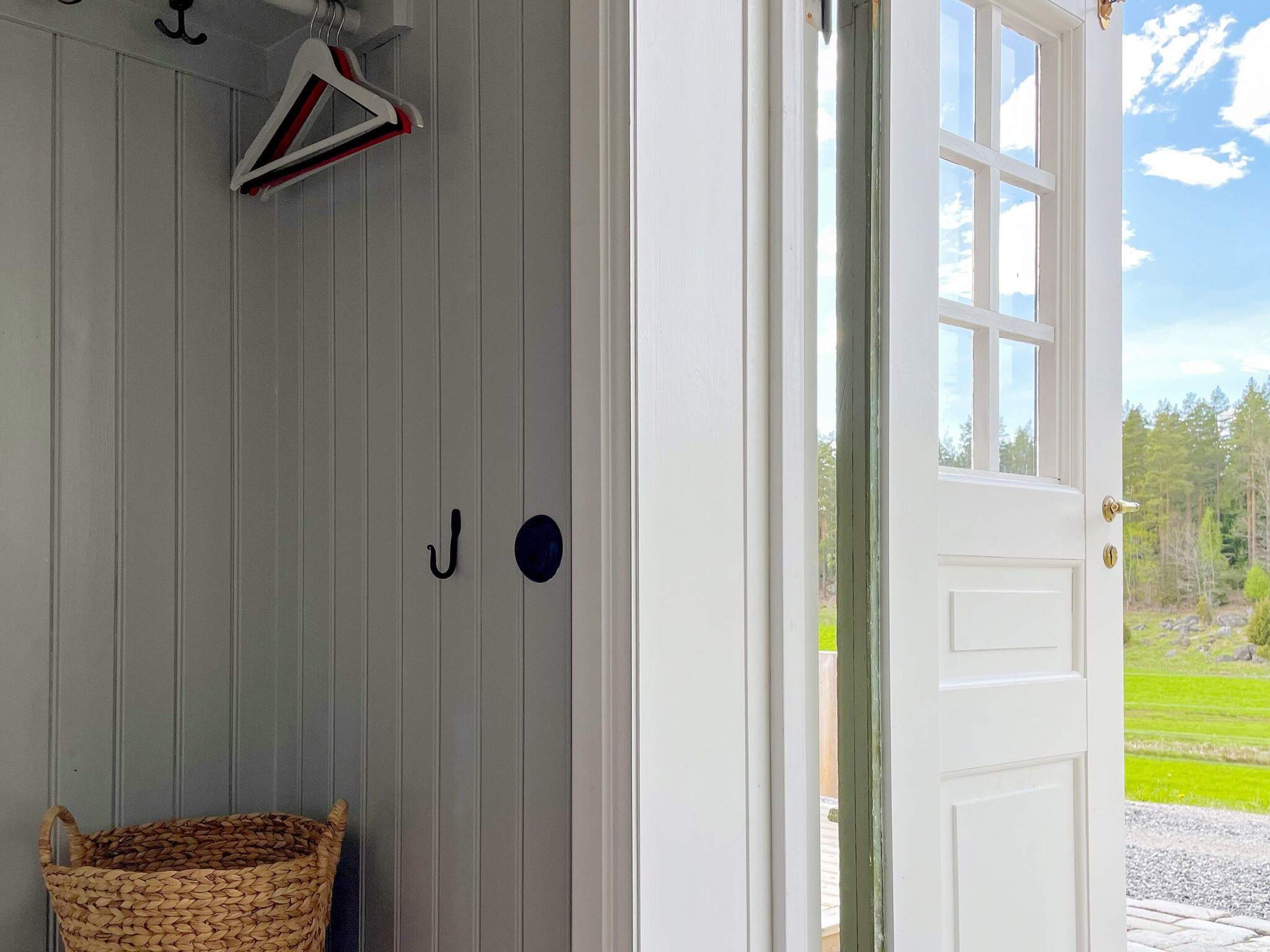 A room with a white door, a hanging coat rack, and a woven basket.